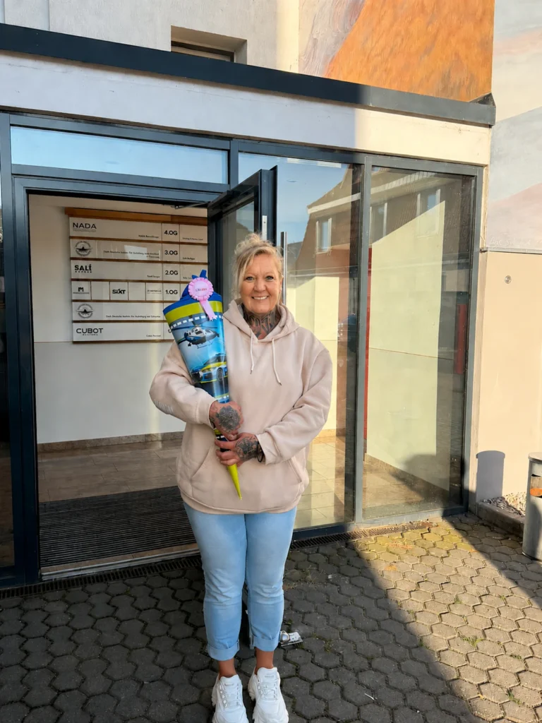 Frau Steinbach hält zum Start ihrer Ausbildung zur Fachkraft für Schutz und Sicherheit eine Zuckertüte vor DIAS Bildung in Leipzig.