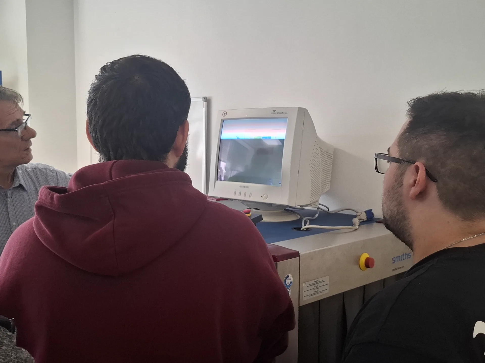 Dozent Herr Feindt bespricht mit zwei Teilnehmern die Anzeige einer Gepäckprüfanlage bei DIAS Bildung in Leipzig.